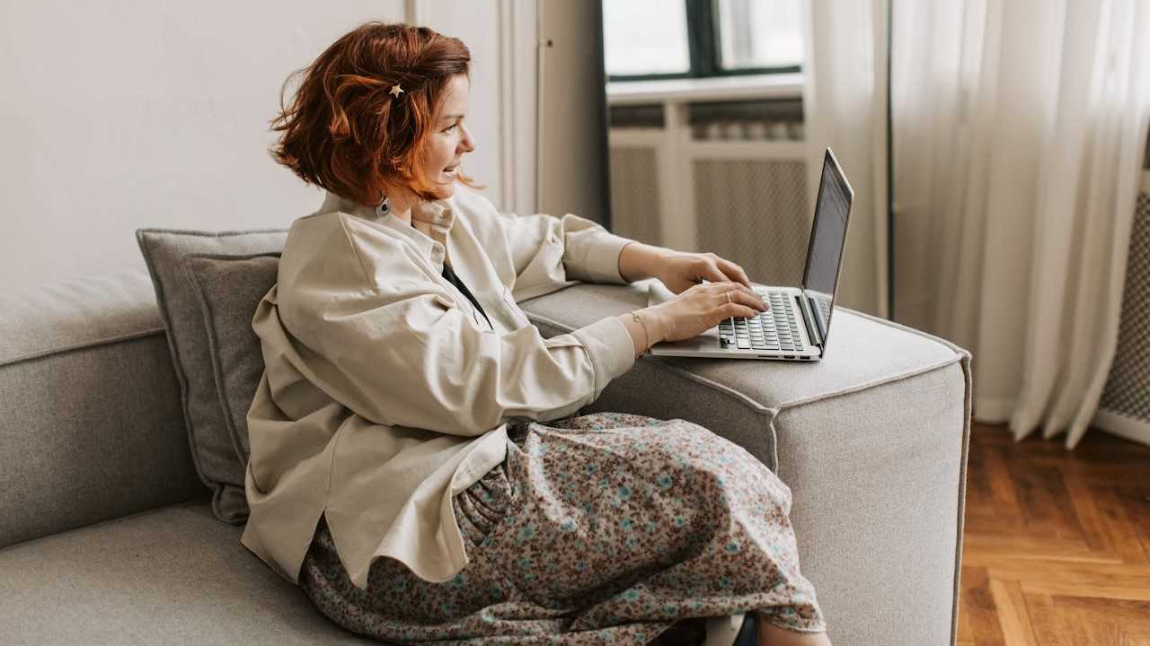 lady using computer sitting on couch-vlada-karpovich