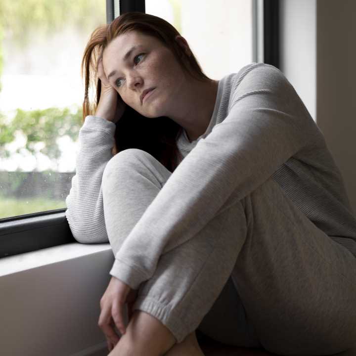 full-shot-sad-woman-near-window