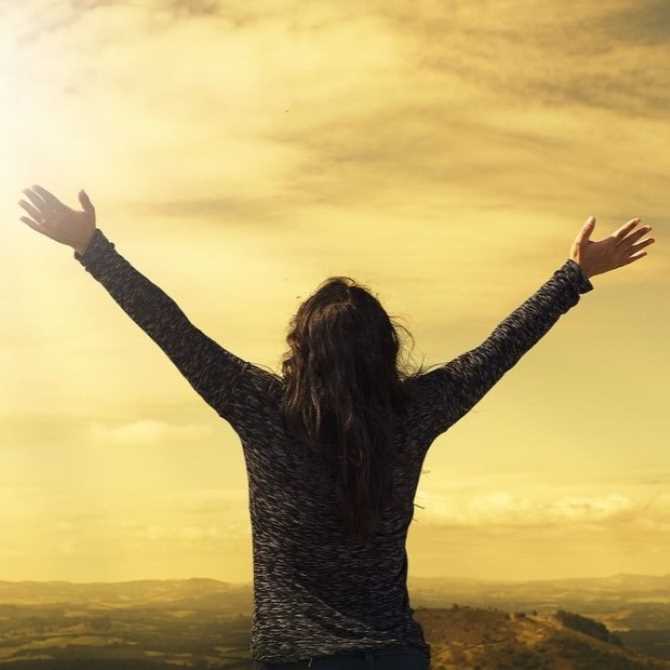 woman with arms raised towards the sun
