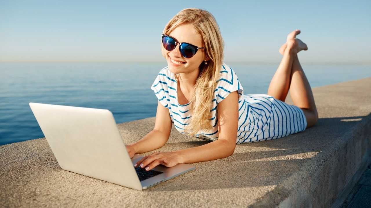 beautiful-young-woman-sitting-beach-with-laptop1