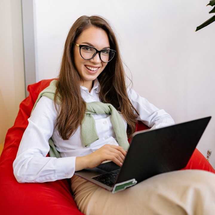smiling girl with laptop sitting on orange chair-yankrukov